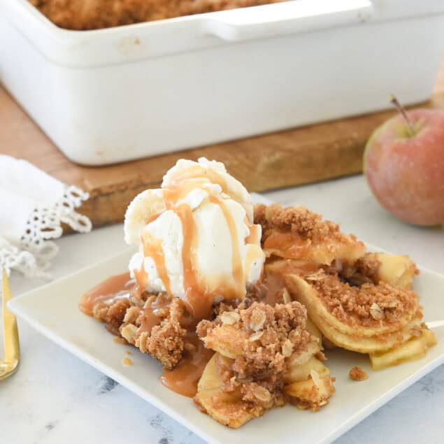 apple crisp on a plate with ice creamand caramel sauce on top