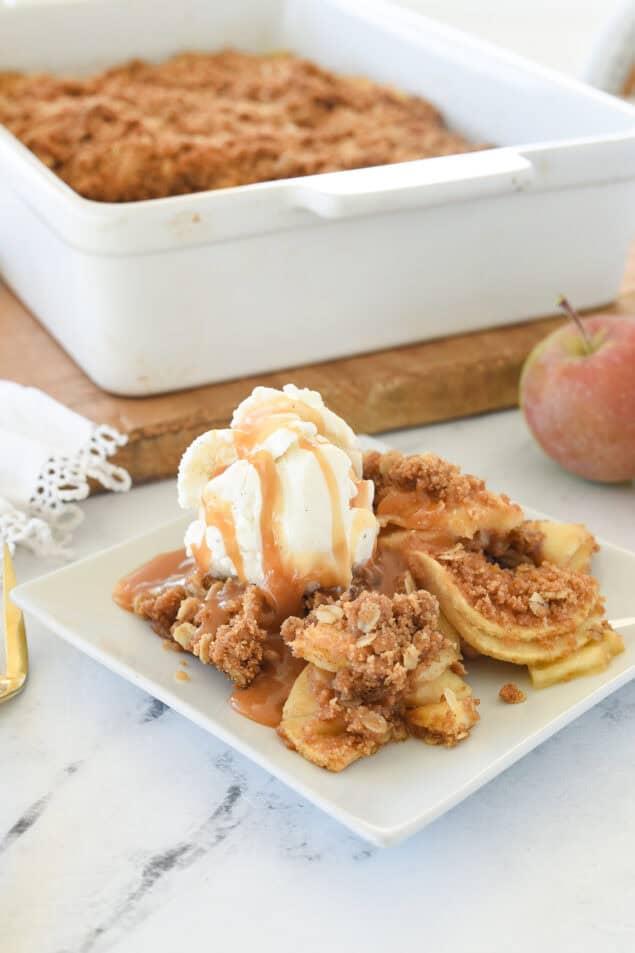 apple crisp on a plate with ice creamand caramel sauce on top