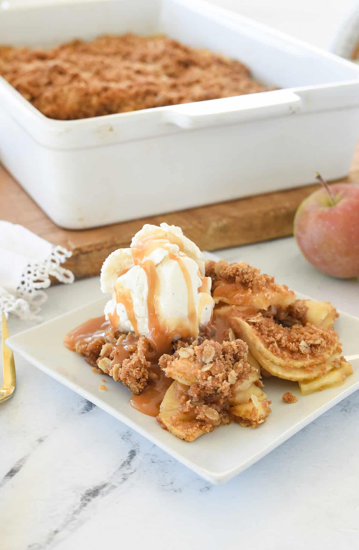 apple crisp on a plate with ice creamand caramel sauce on top
