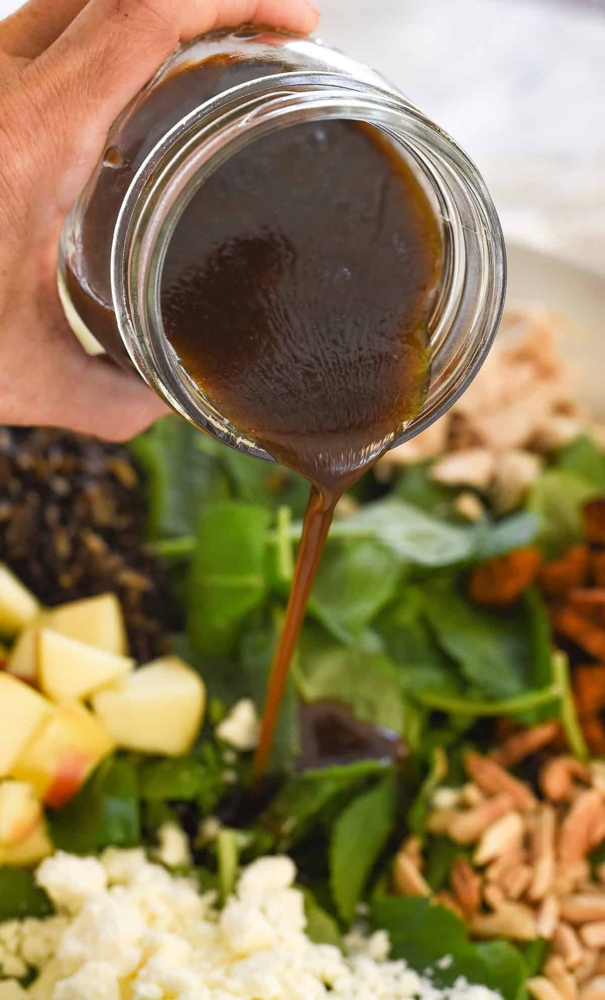 pouring balsamic vinaigrette over salad