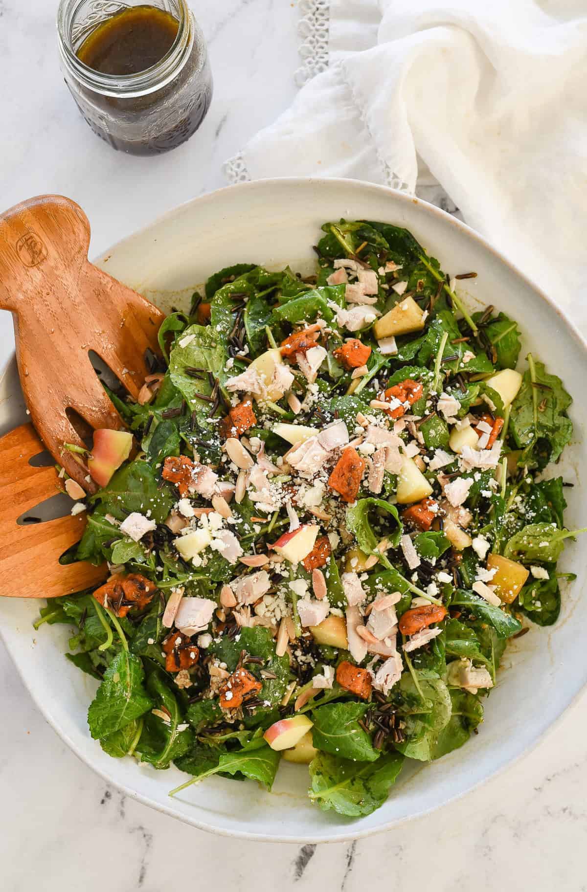 overhead shot of bowl of harvest salad with dressing in a jar