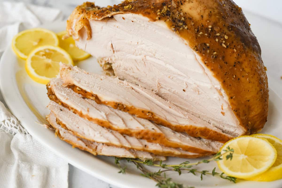 side view of carved turkey breast on a white platter