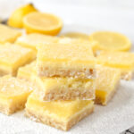 stack of 3 lemon cheesecake bars on white parchment paper
