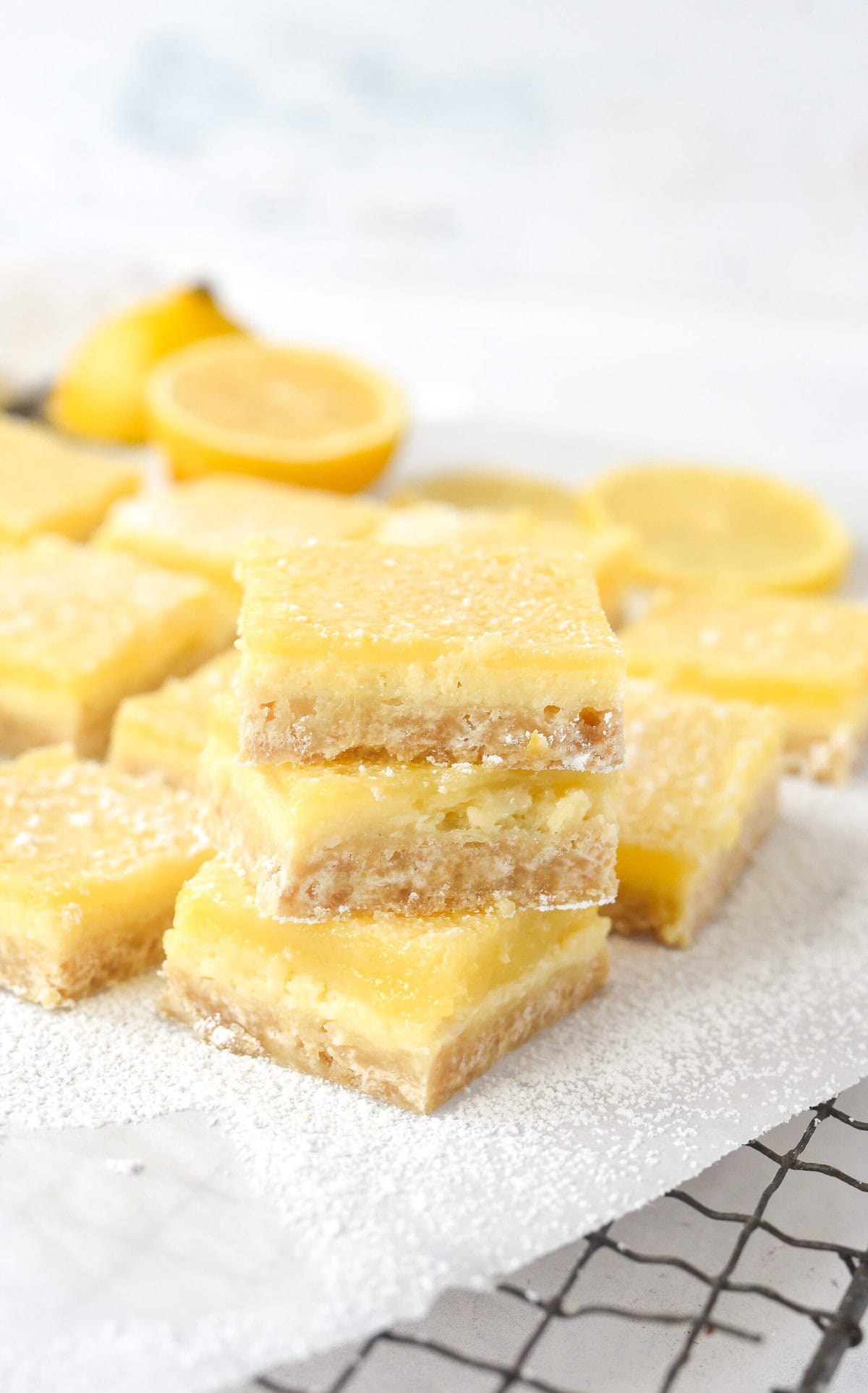 stack of 3 lemon cheesecake bars on white parchment paper