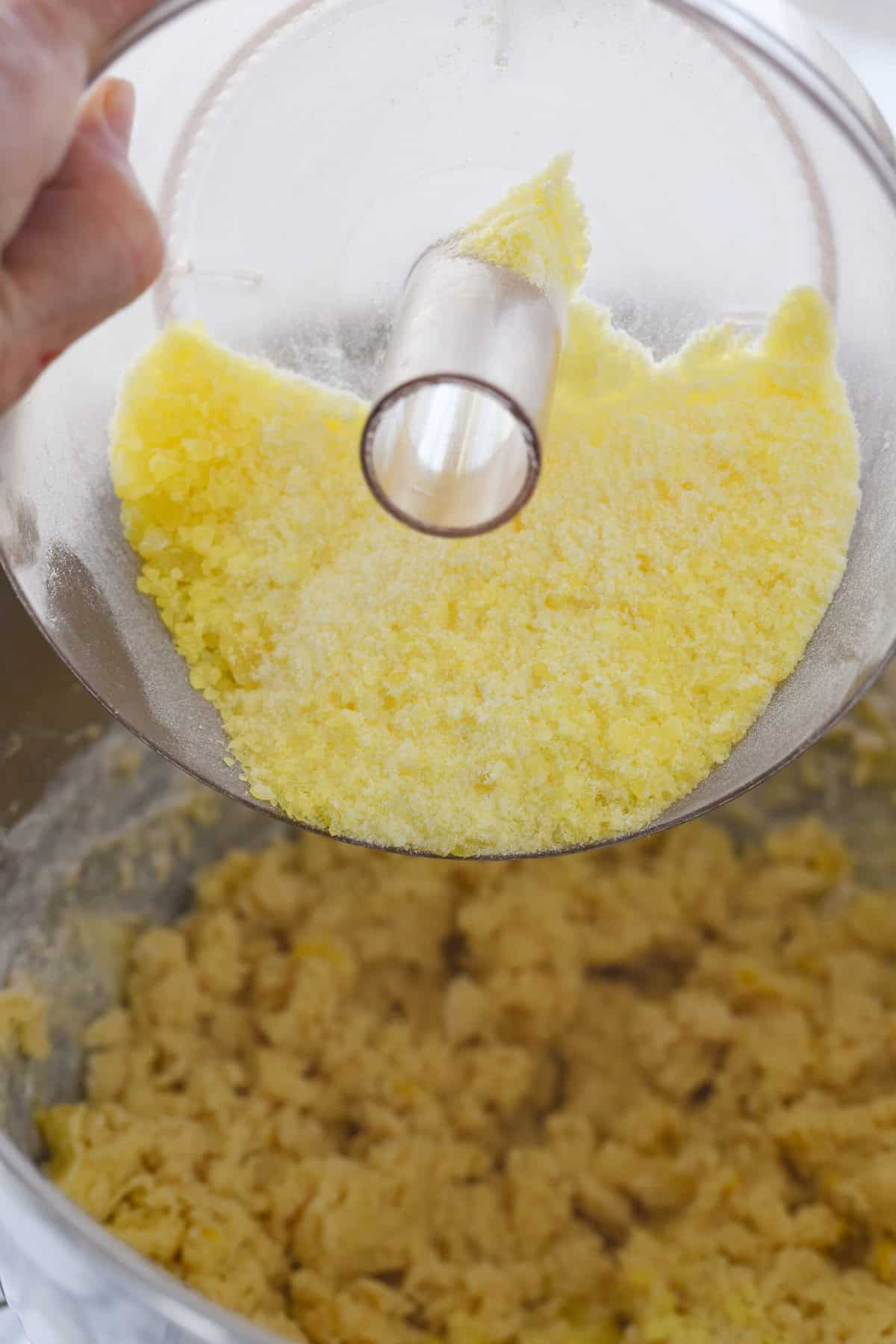 pouring crushed lemon drops into cookie dough.