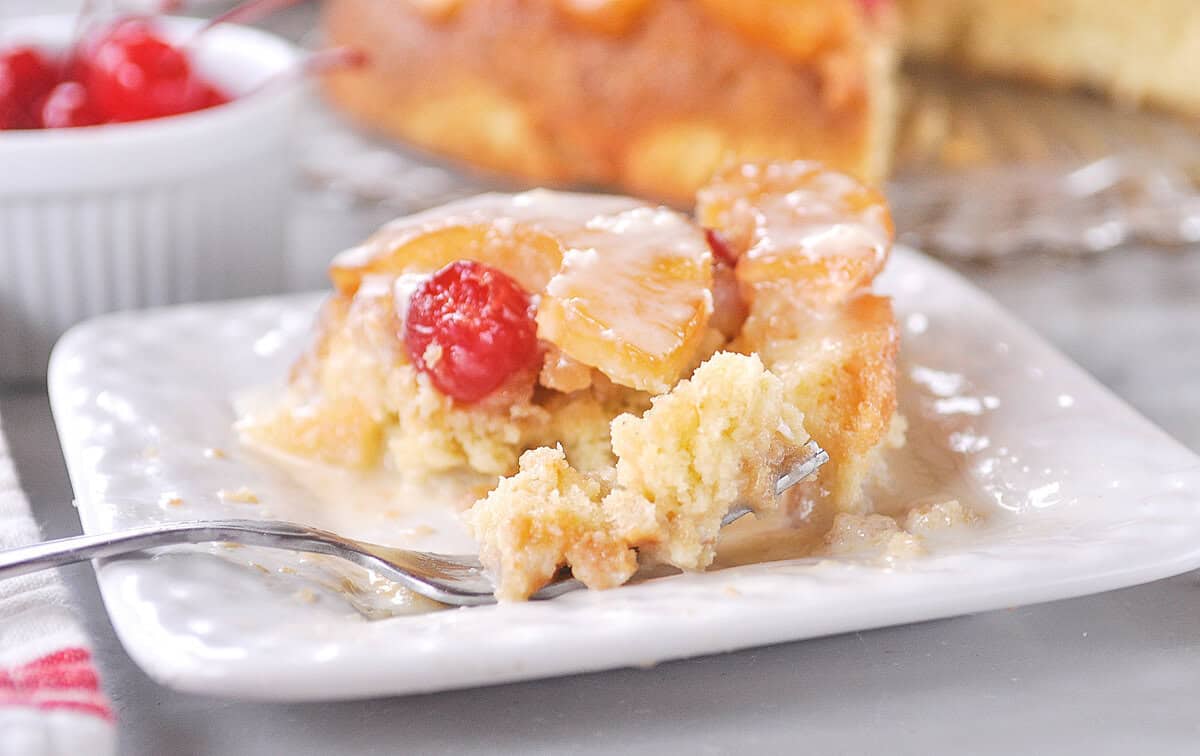 fork full of pineapple upside down cake with vanilla sauce on it