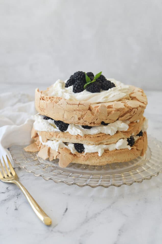 brown sugar pavlova with whipped cream and berries on top on a clear glass plate