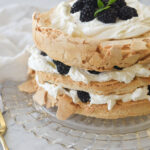 brown sugar pavlova on a plate with blackberries on top