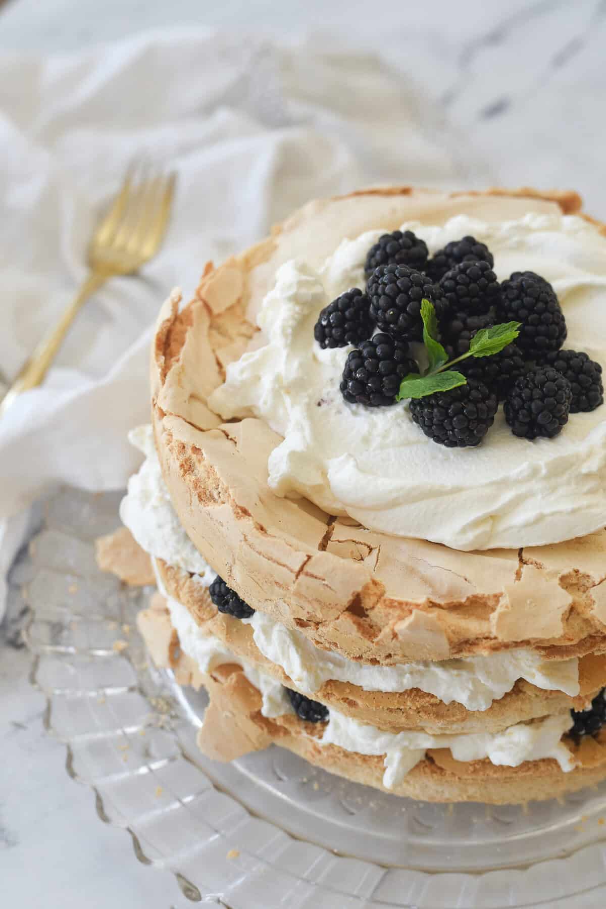 view of brown sugar pavlova for the top with whipped cream and berries on it.