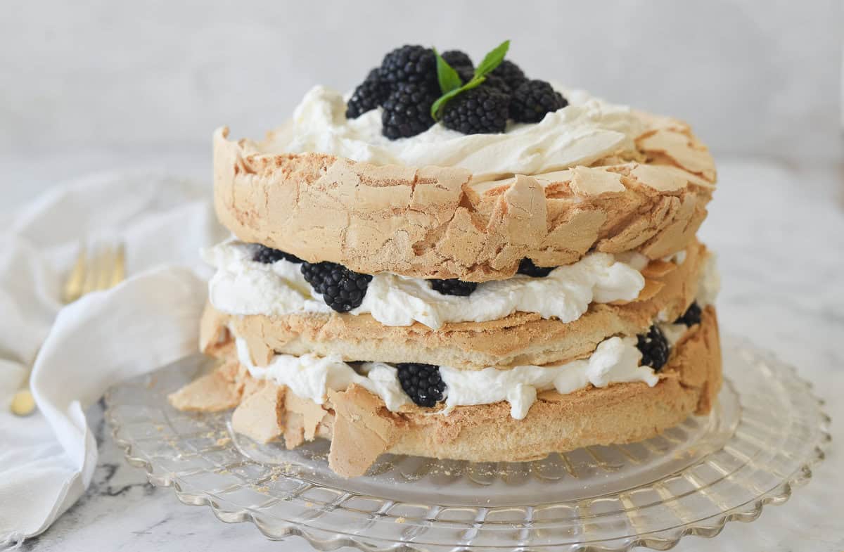 brown sugar pavloa with whipped cream and blackberries on a plate