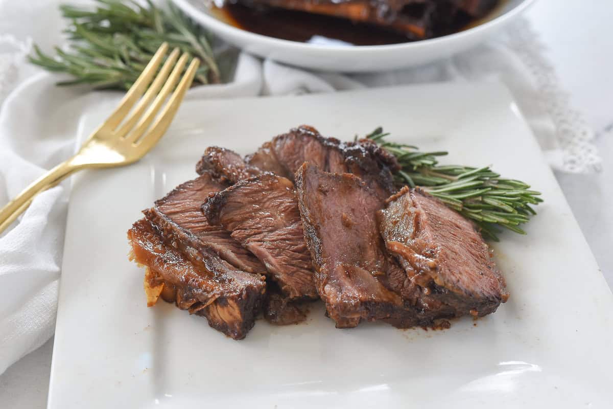 sliced shortrib on a plate with rosemary