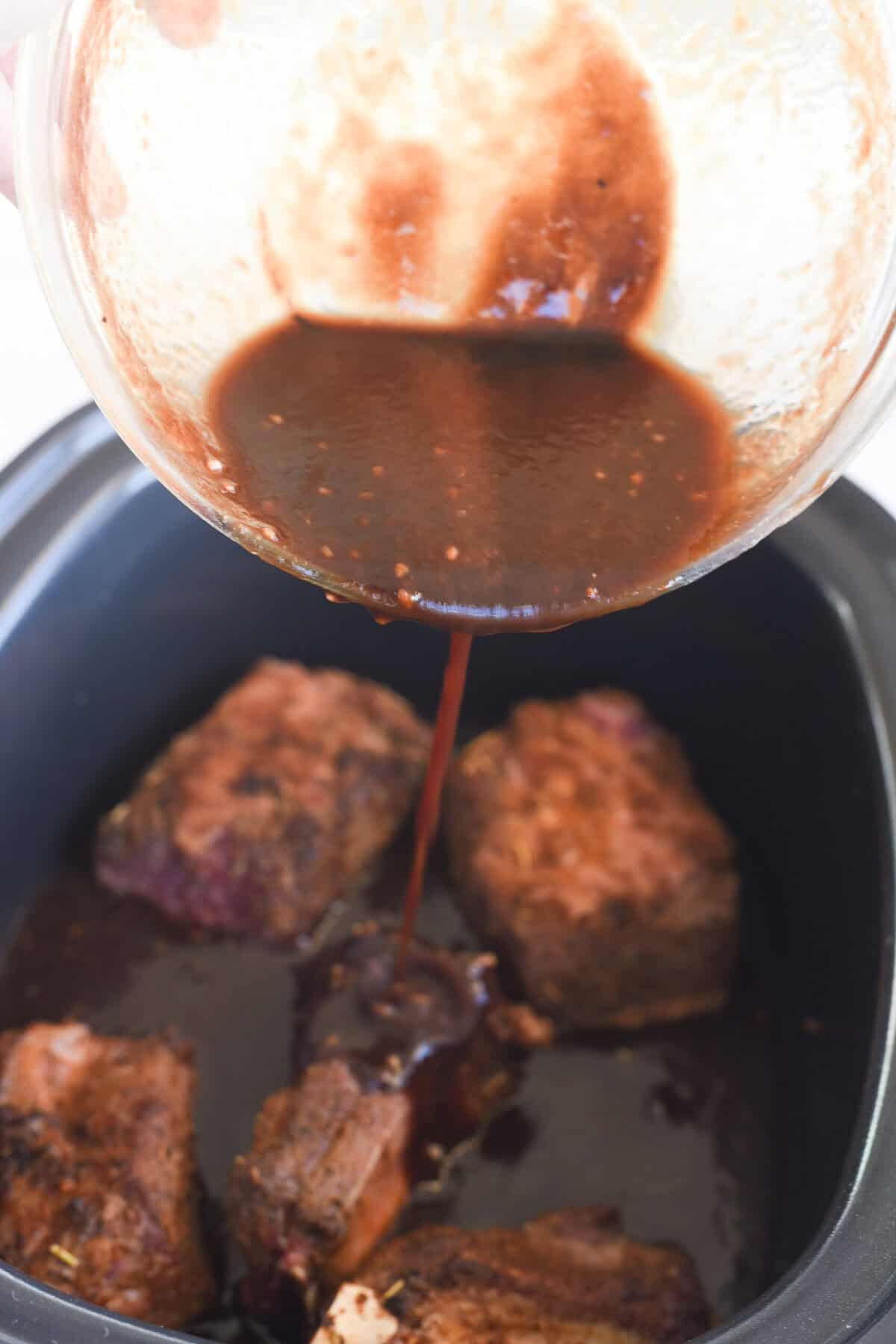 Pouring sauce over ribs in slow cooker