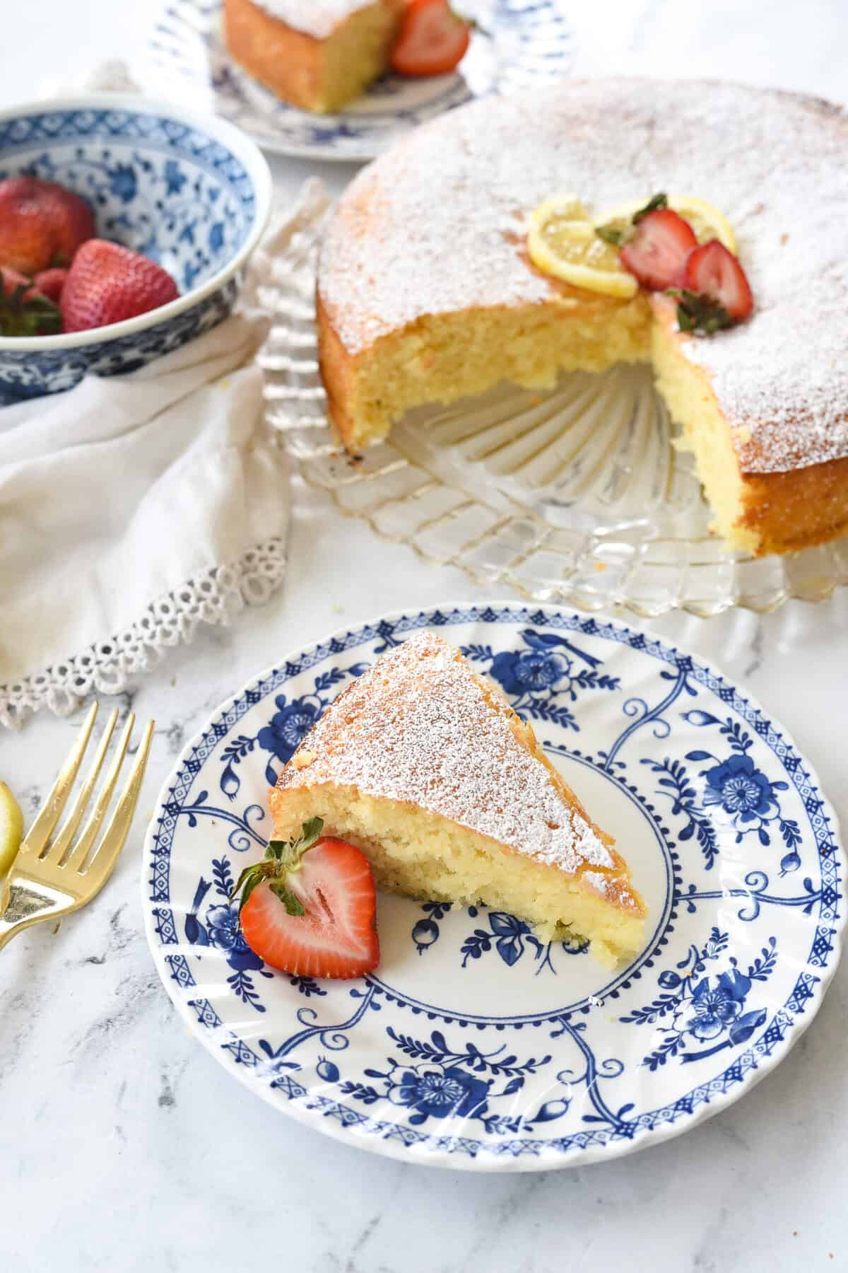 overhead shot of lemon ricotta cake on a plate with a slice of cake on another plate.