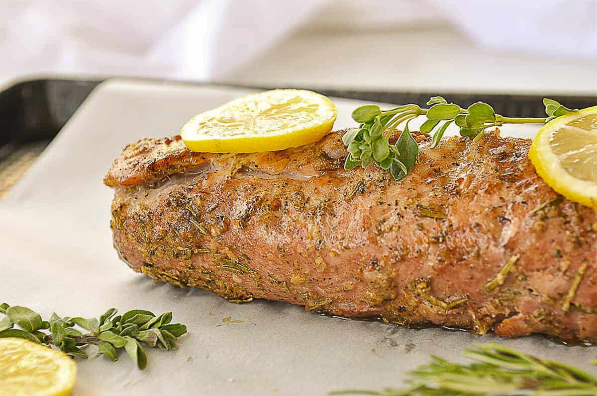 lemon pork tenderloin with a slice of lemon and herbs on top