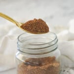 spoonful of taco seasoning above a jar