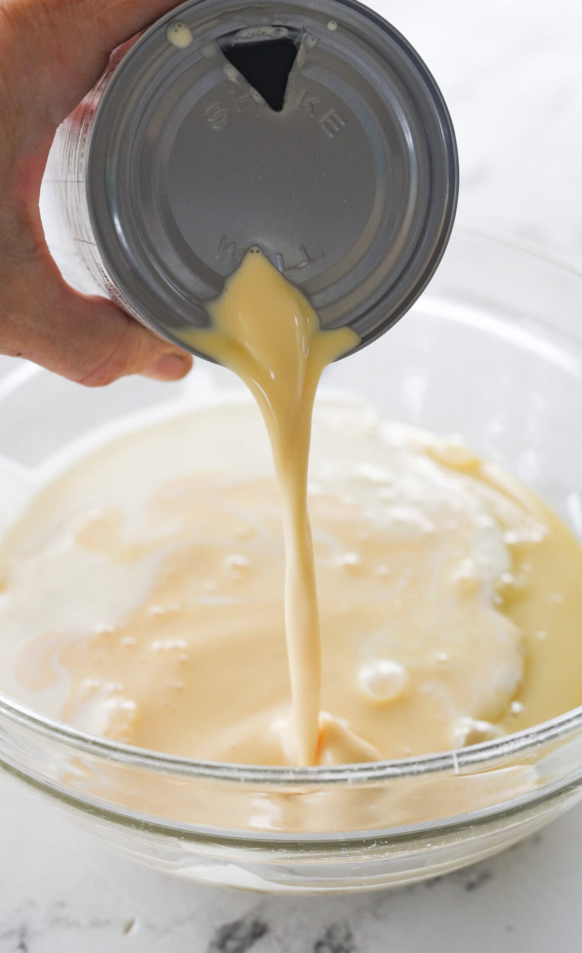 combining milks into a bowl for tres leches cake
