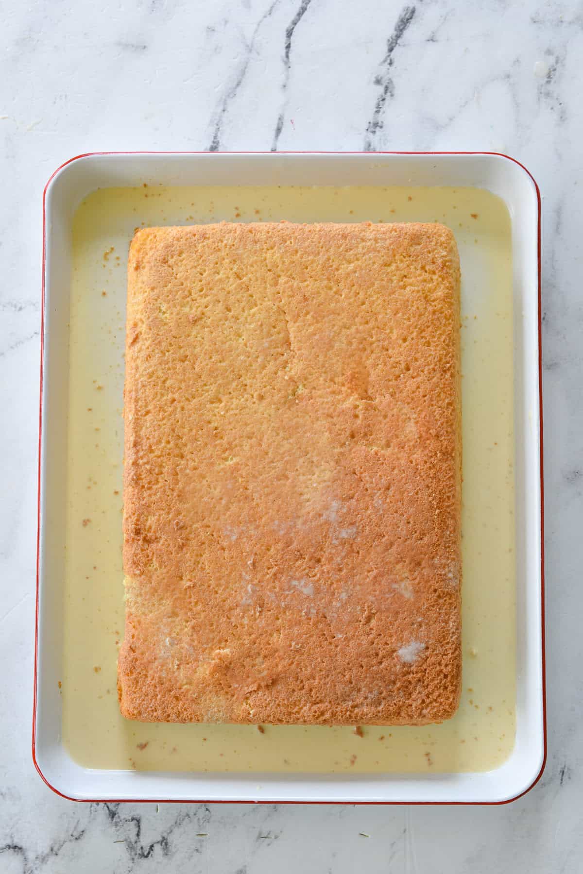 milk poured over top of tres leches cake

