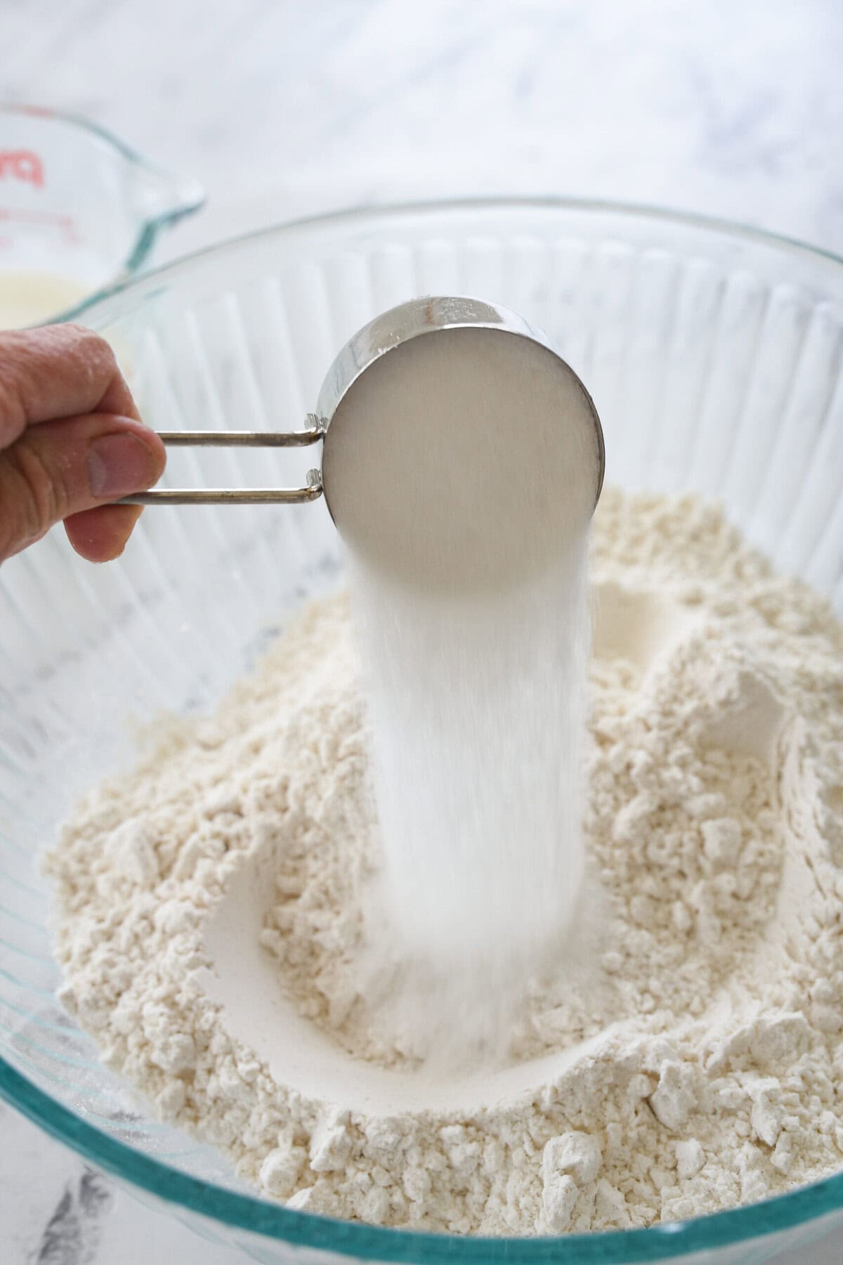 adding sugar to flour in a bowl
