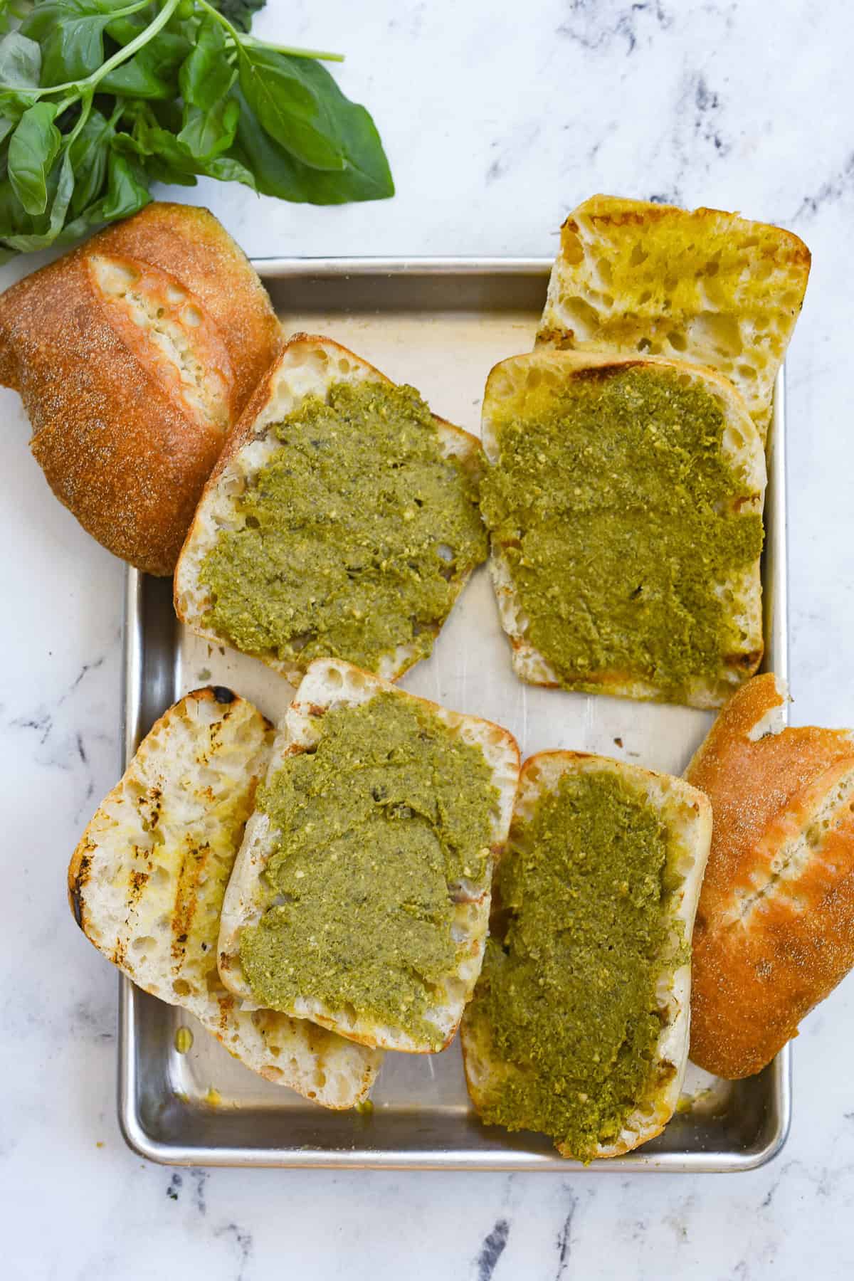 overhead shot of grilled bread with a layer of pesto on it
