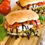 two chicken caprese sandwiches on a cutting board