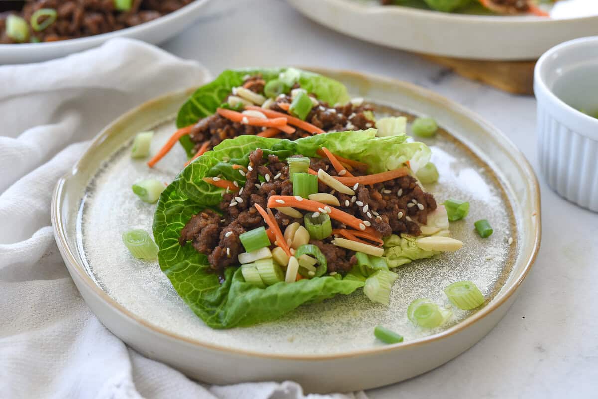 a plate with two beef lettuce wraps on it
