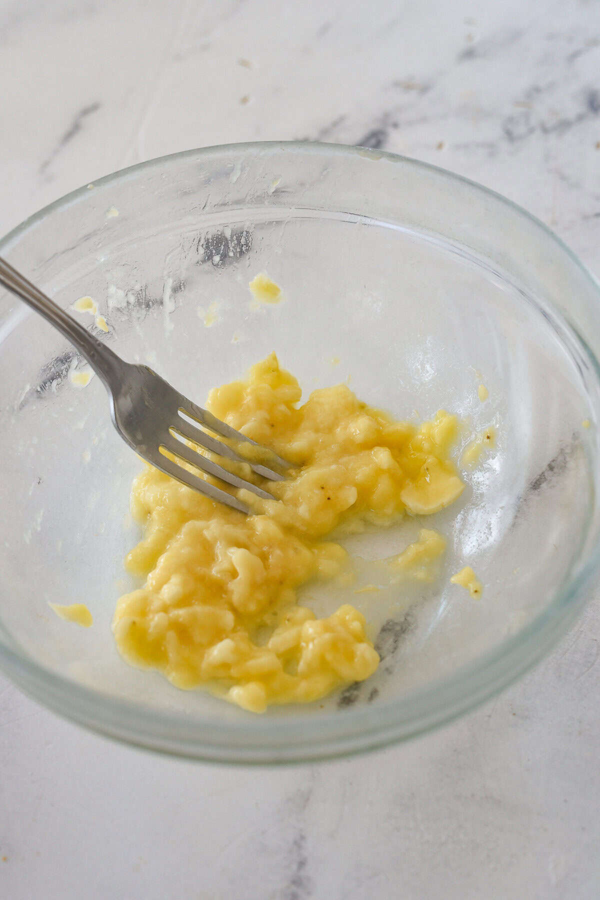 smashing a banana in a bowl with a fork.
