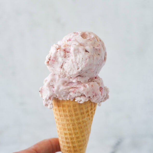 strawberry ice cream cone in a hand.