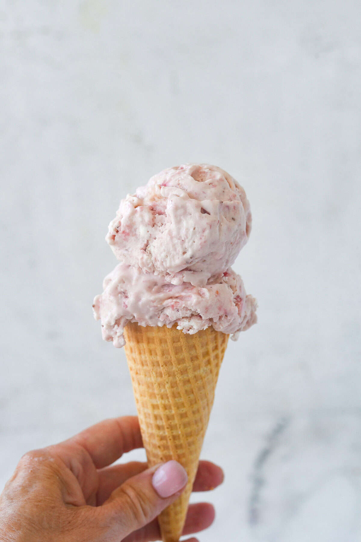 strawberry ice cream cone in a hand.