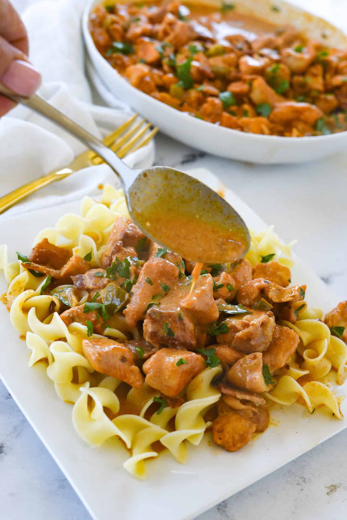 pouring sauce over chicken paprikash
