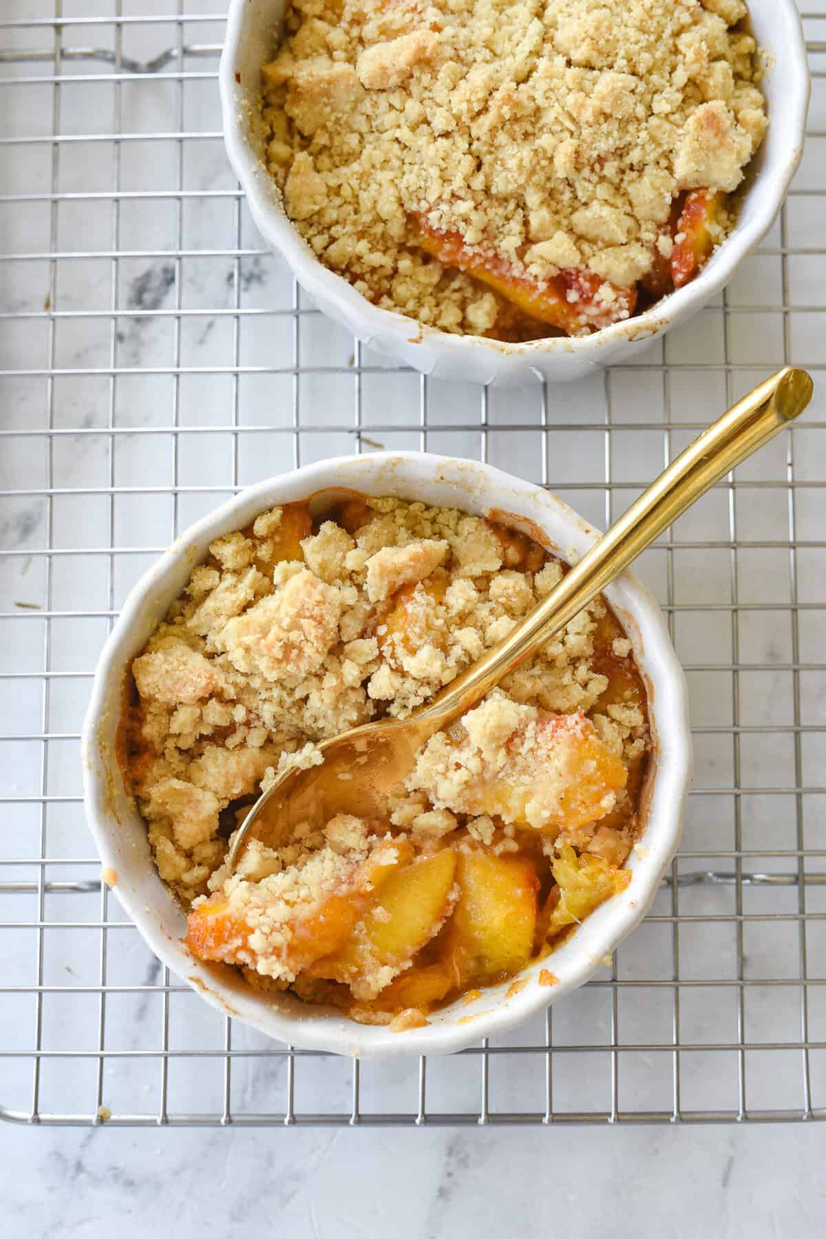 closeup of peach cobbler in a ramekin with a spoon.