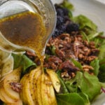 pouring poppy seed dressing over a salad