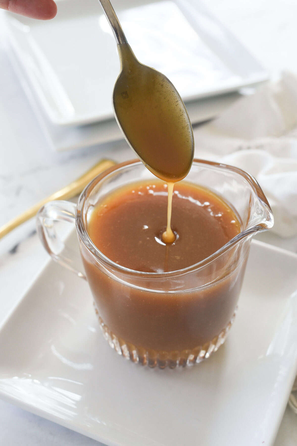 spoon drippign cramel sauce into a pitcher