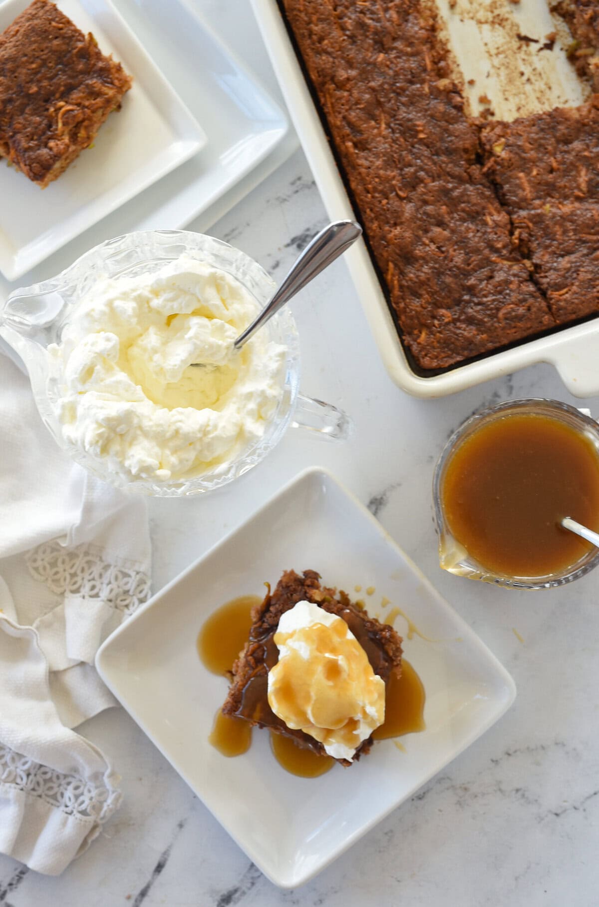 overhead shot of apple cake with whipped cream and caramel sauce