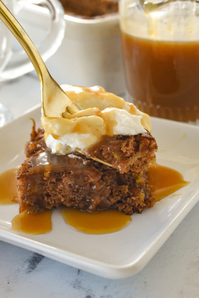 forkfull of apple cake with whipped cream on top