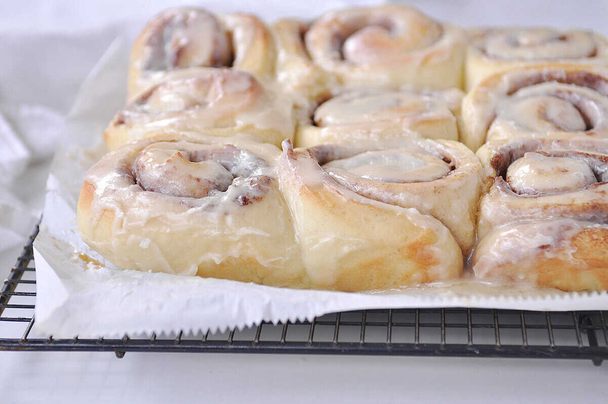 side view of a pan of cinnamon rolls on a cooling rack