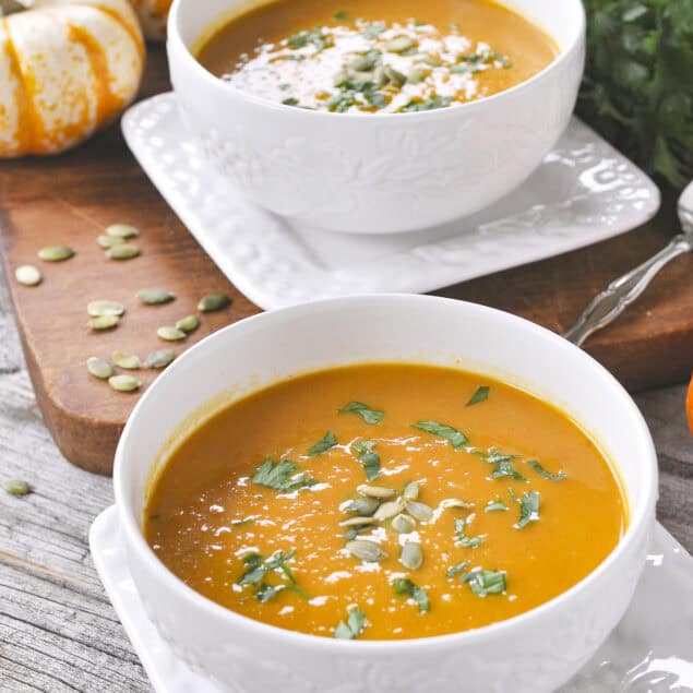 two white bowls full of pumpkin curry soup