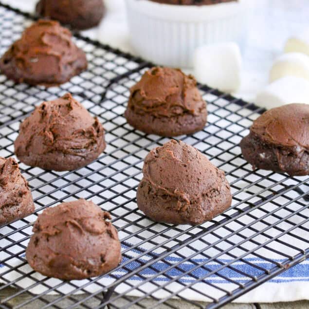 chocolate marshmallow cookies on a cooling rack on top of a kitchen towel