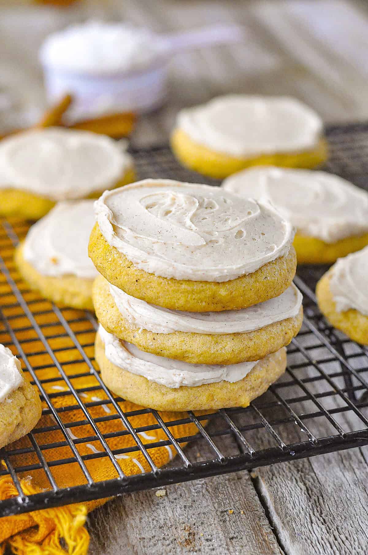 stack of frosted pumpkin sugar cookies on rack