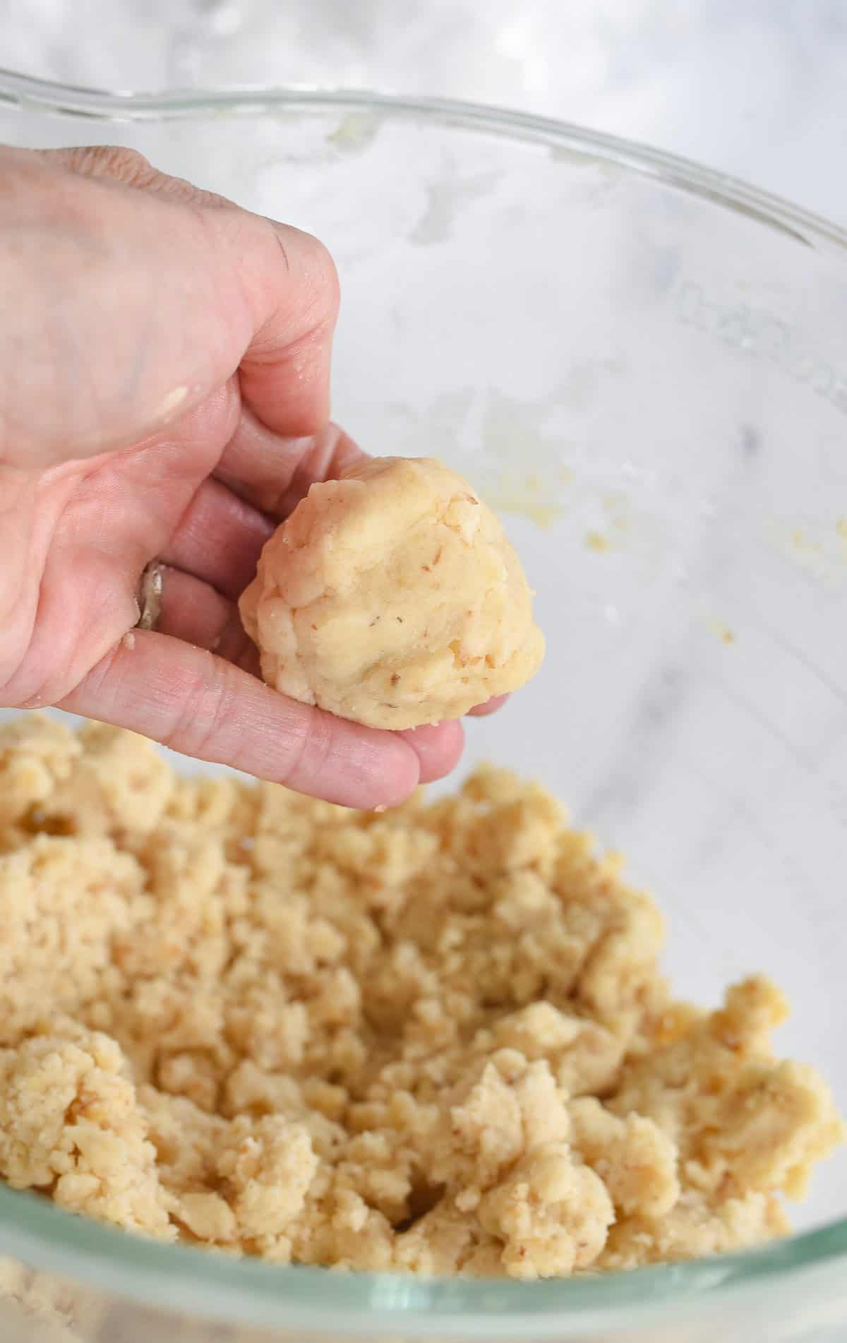 hand holding a dough ball for snowball cookies