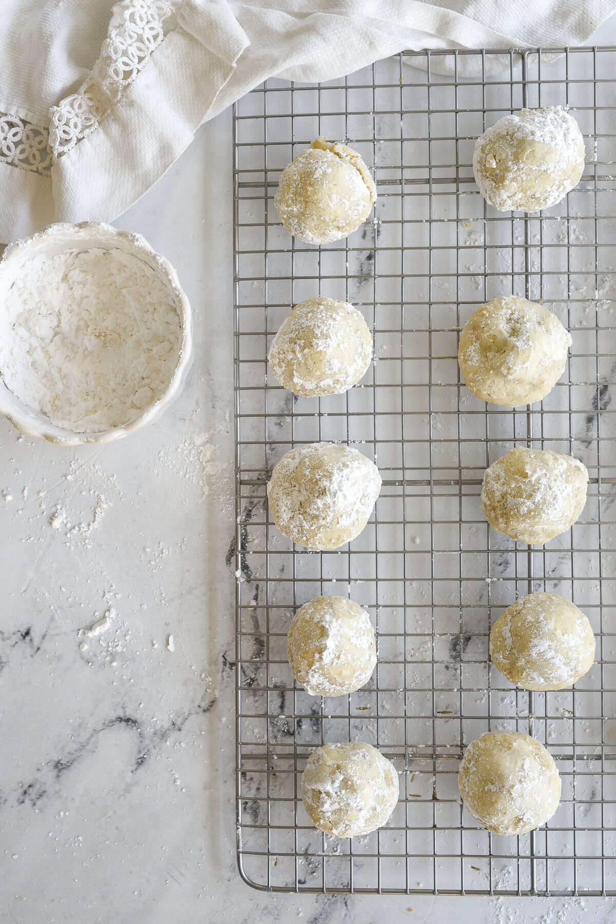 overhead shot of puttng snowball cookies in powdered sugar
