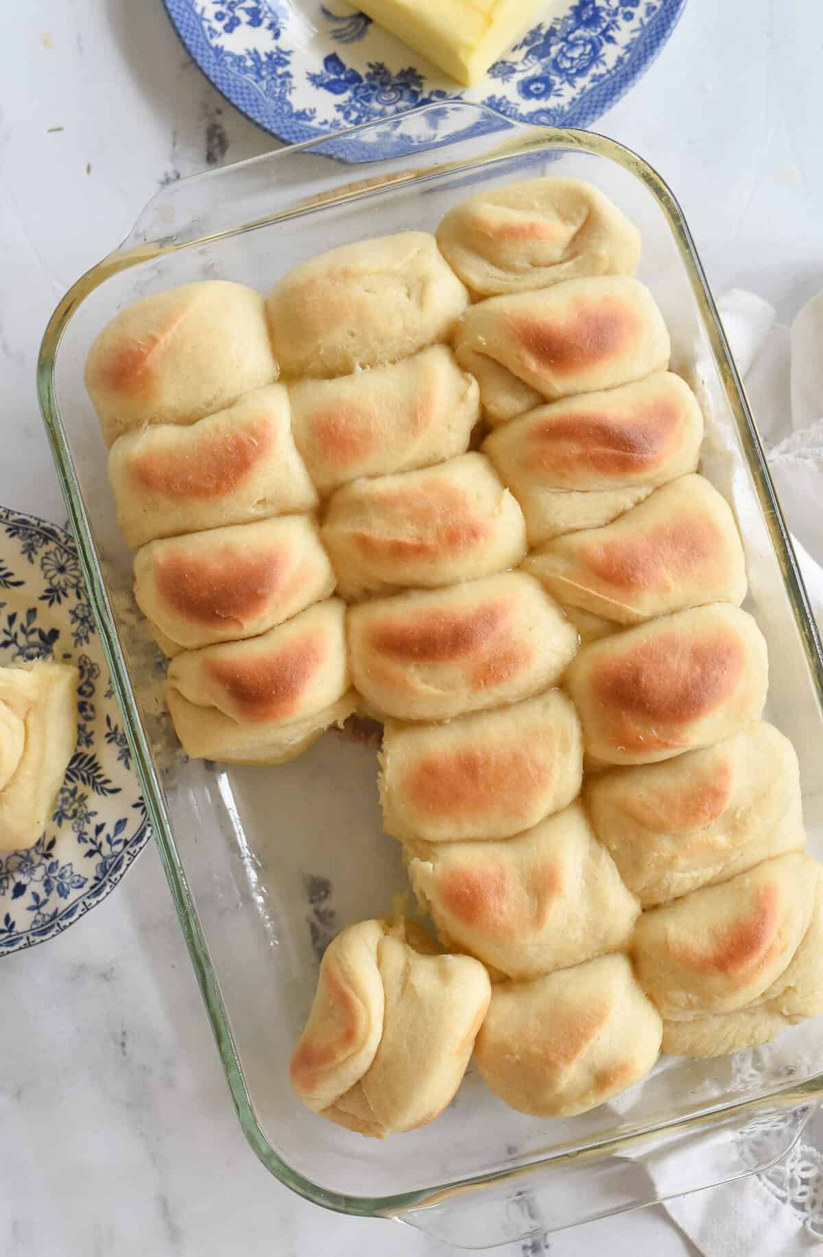overhead shot of parkerhouse rolls with plate of butter