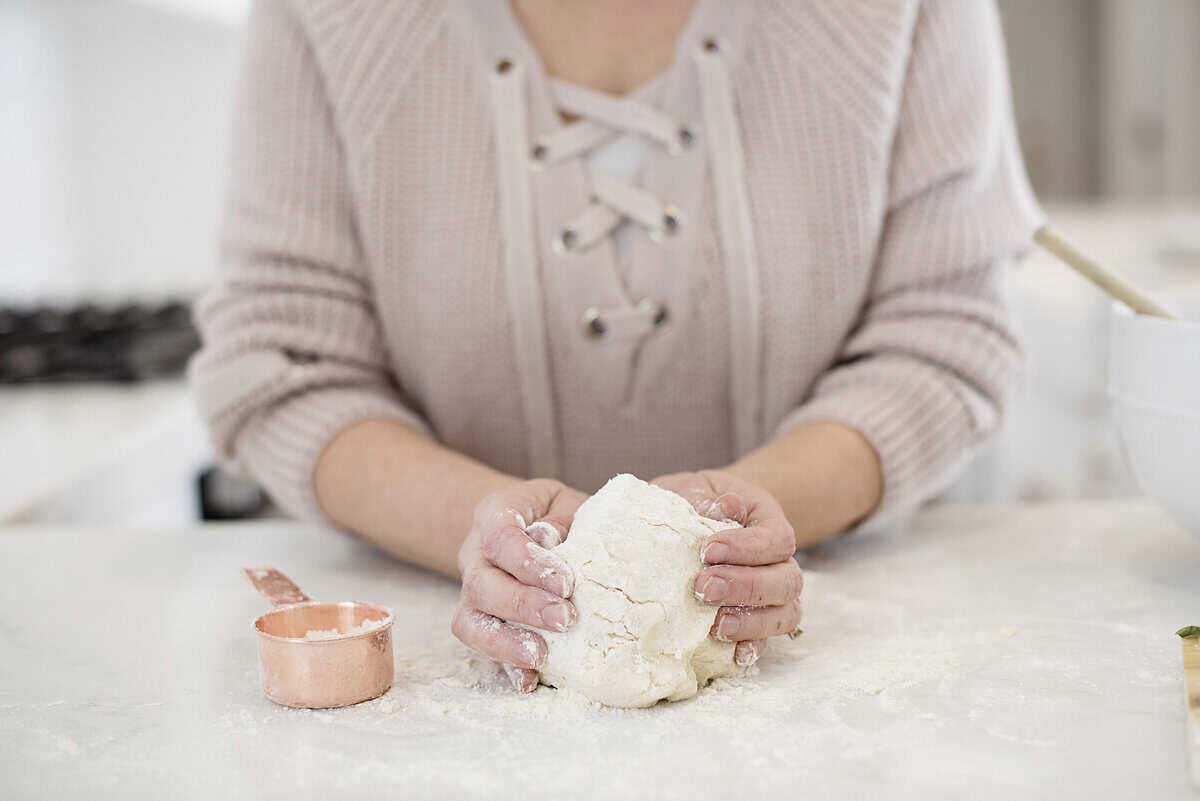 hands holding biscuit dough on counter