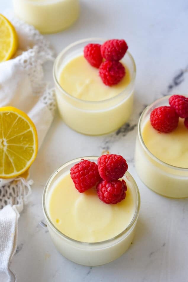 glass dshes of lemon posset with raspberries on top