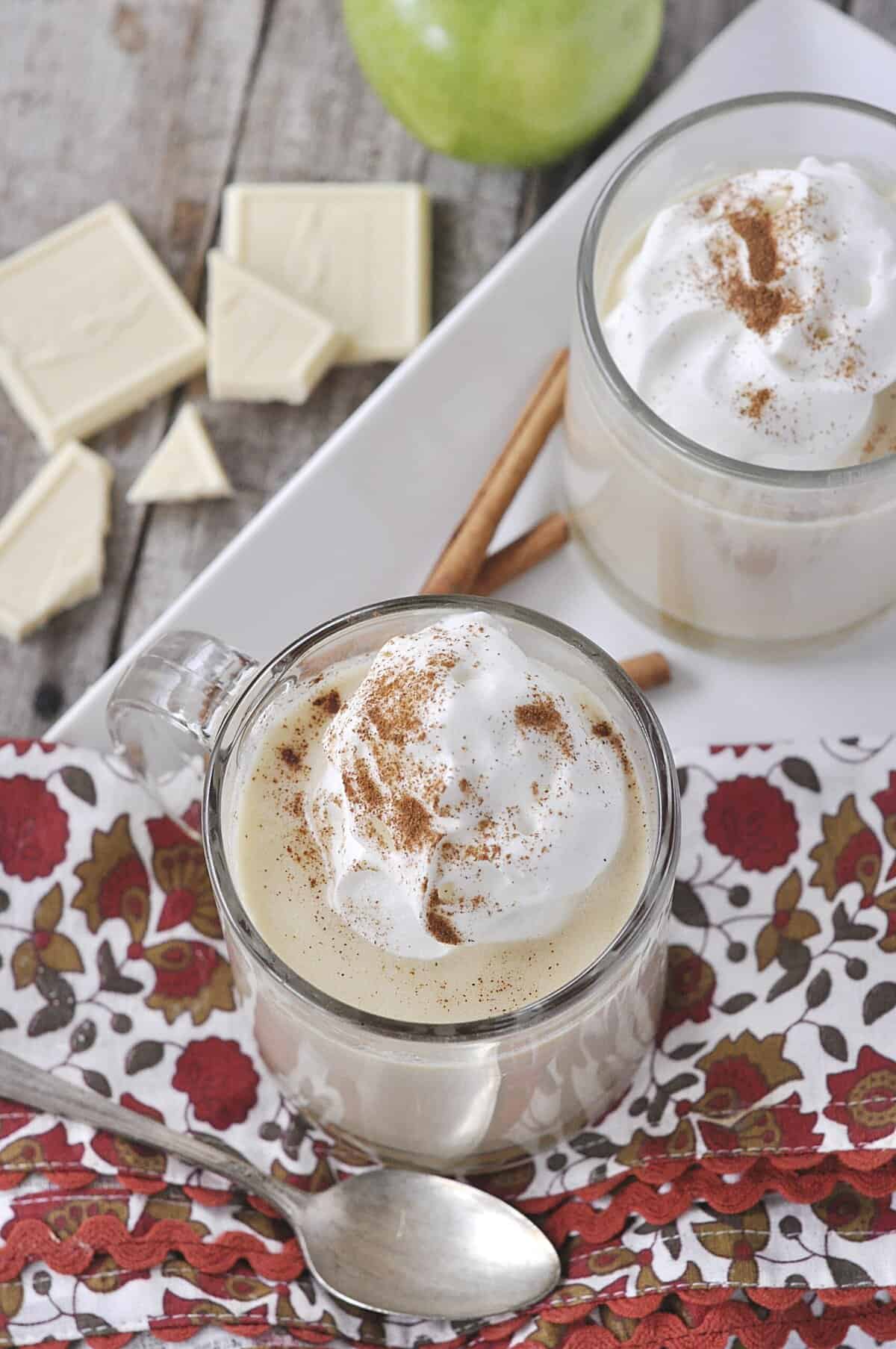 two mugs of apple cider hot chocolate on a white tray