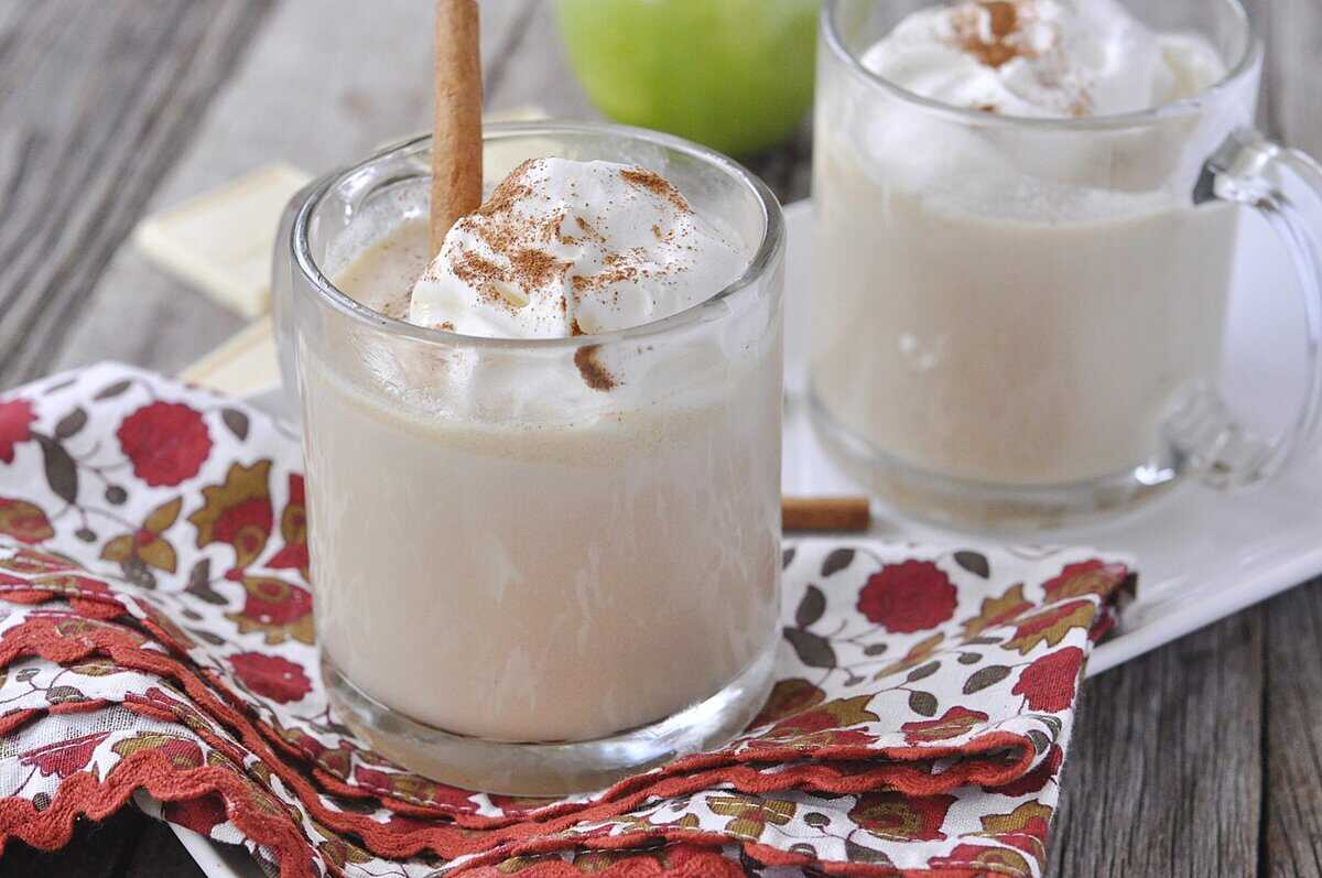 two mugs of apple cider hot chocolate with whipped cream on top