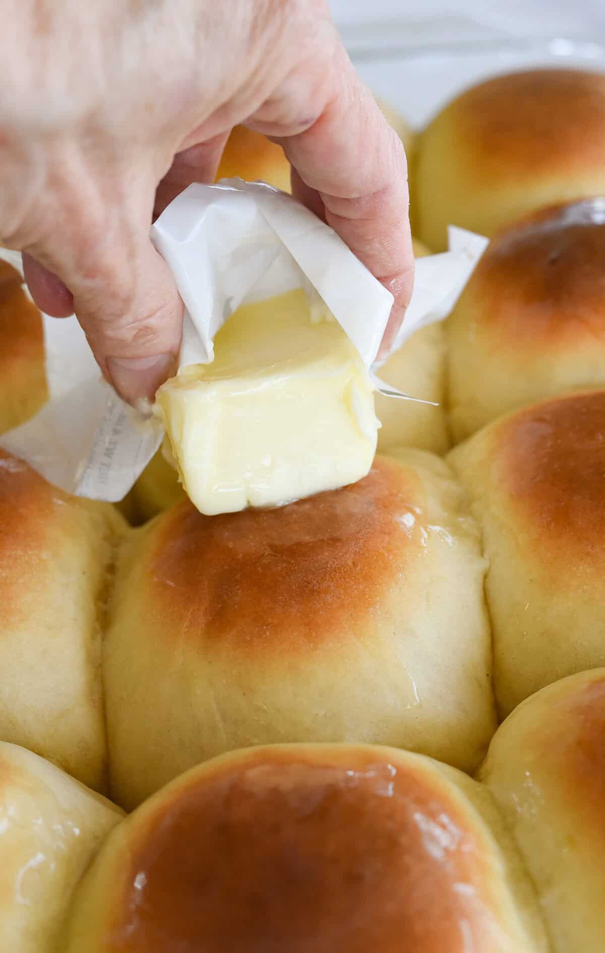 rubbing butter over top of rolls