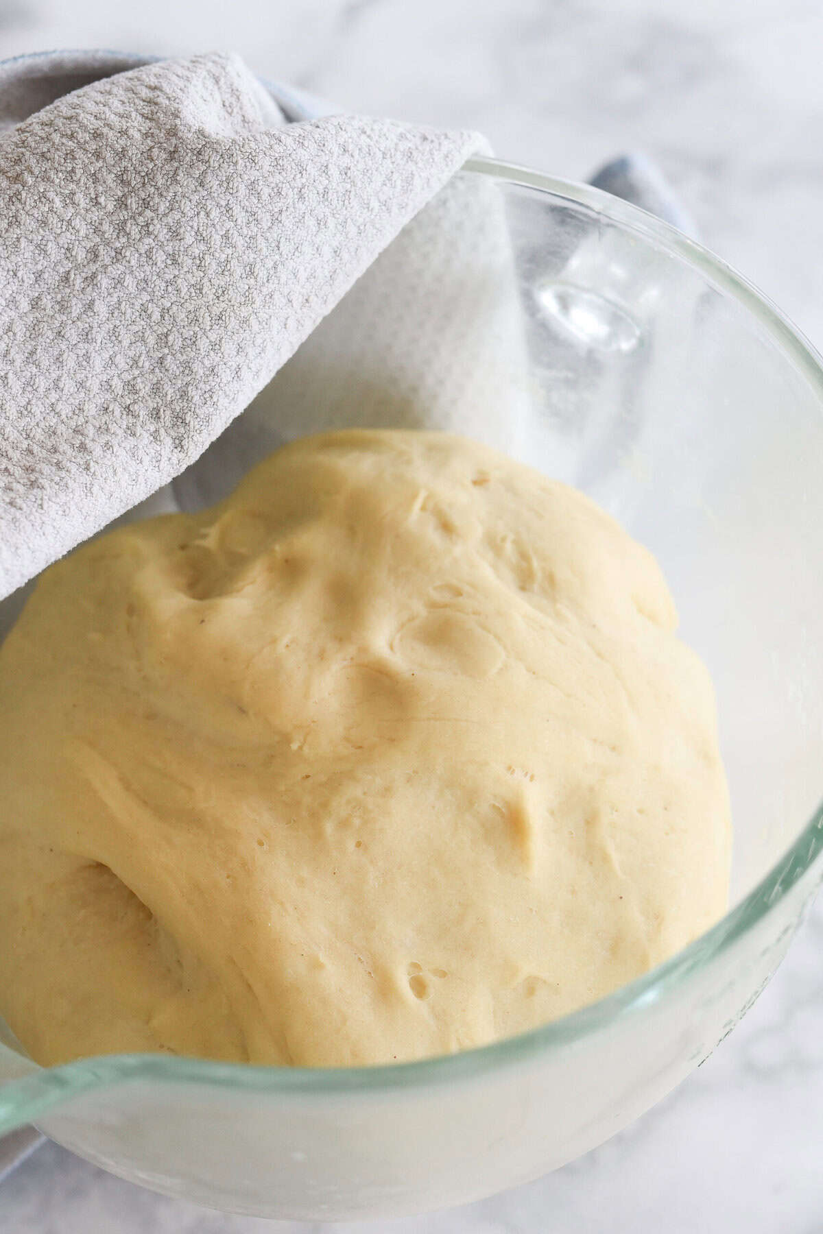 risen potato roll dough in a bowl