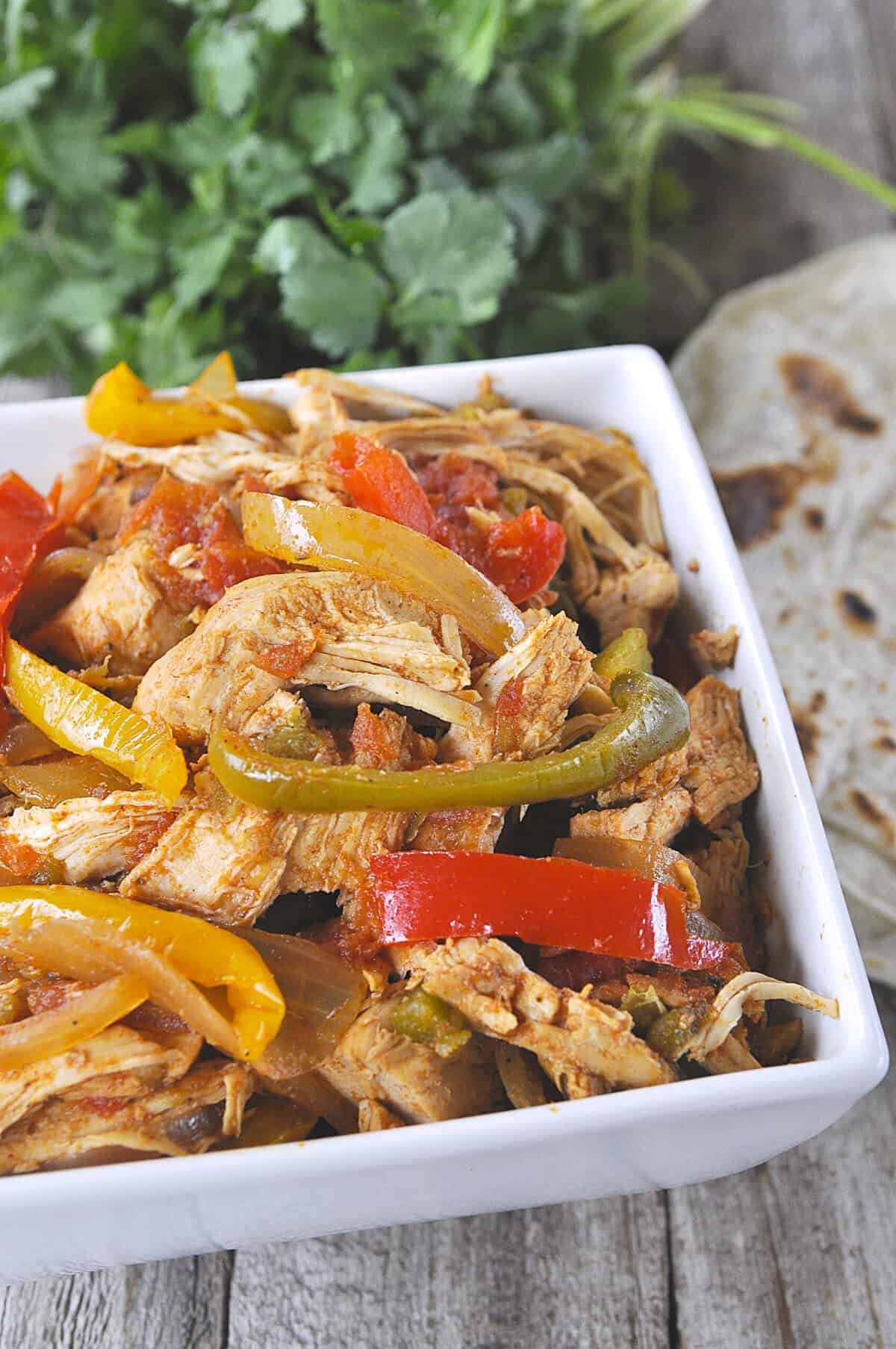 slow cooker chicken fajita meat in a bowl with peppers