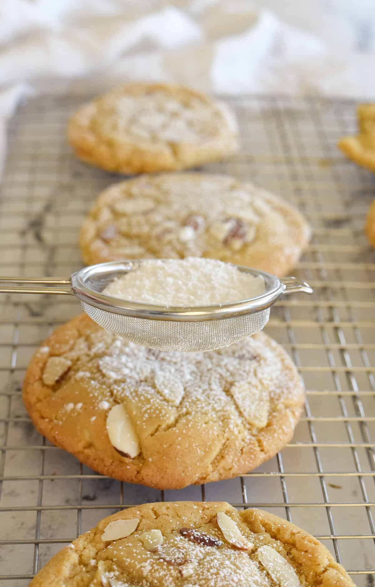 sprinkling almond croissant cookies with powdered sugar