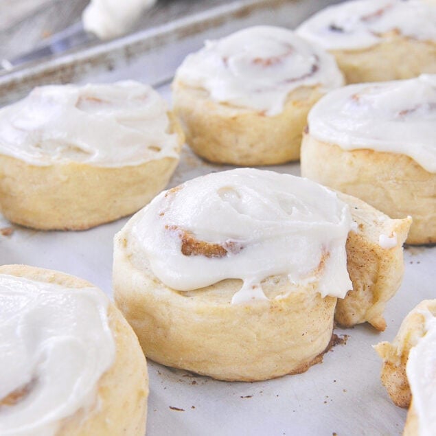 frosted cinnamon rolls on a baking sheet
